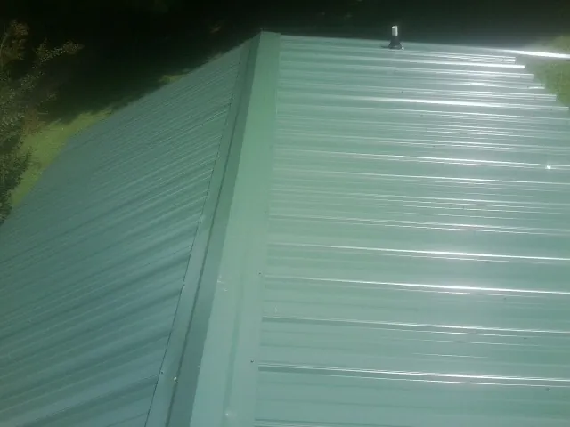 New green metal panels meeting at the ridge of a roof — Flat Roof Repair work by our crew in Elbow Lake