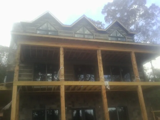 Dormers and porch framing on a large log home under construction — Roof Coating work by our crew in Elbow Lake