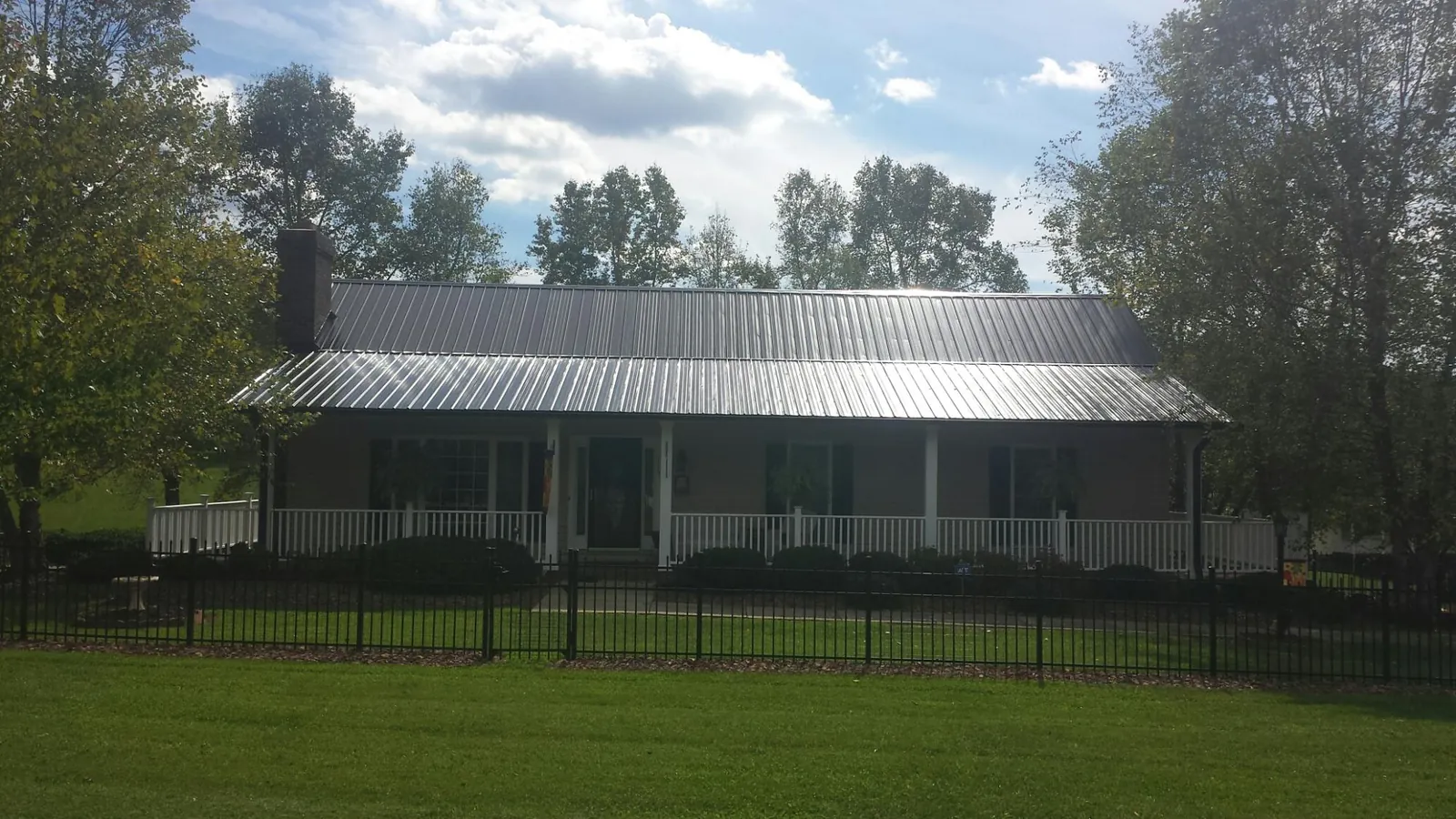 Gray metal roof on a brick ranch with a full width front porch — Gutter Guard Installation work by our crew in Elbow Lake
