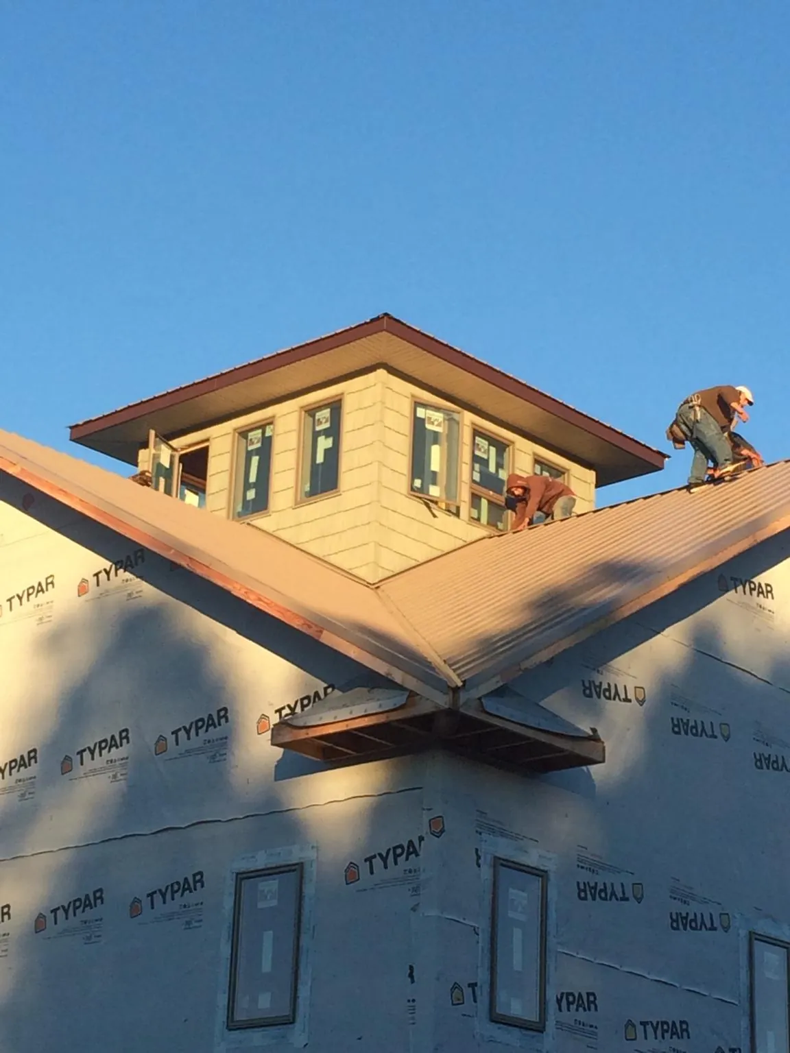 Roofers working around a rooftop cupola on a new metal roof at sunset — Roof Waterproofing in Elbow Lake by Roofing Brothers